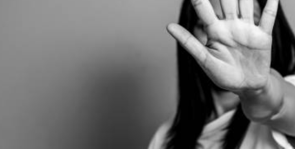 En person håller upp handen mot kameran med handflatan framåt, vilket delvis skymmer ansiktet.